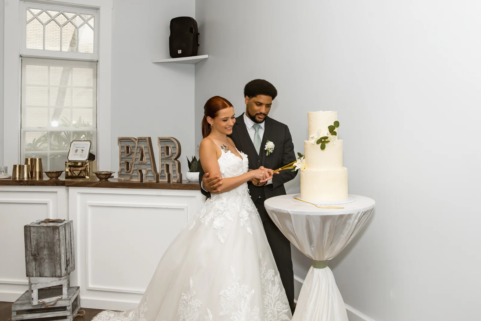 A couple cutting their cake at Heller Hall with the WinterBrooke bar behind them